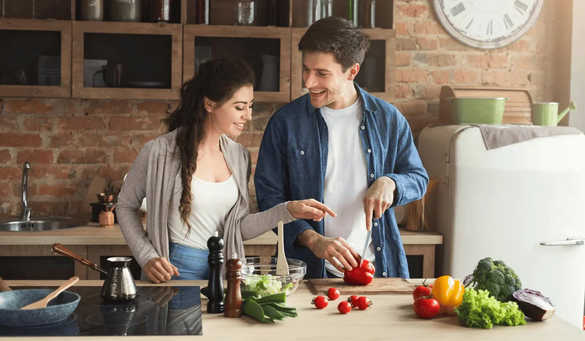 A happy couple preparing fresh ingredients together in a home kitchen.