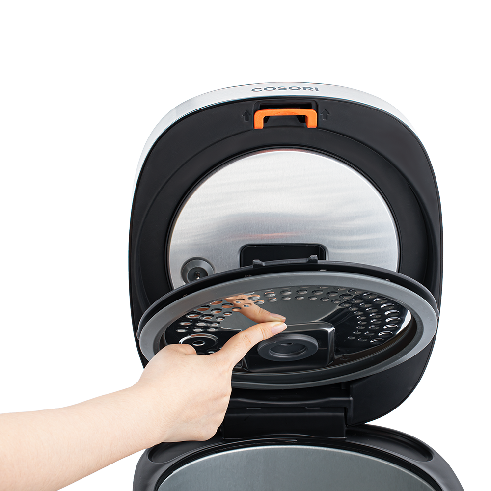 Hand demonstrating how to remove the inner lid of the Cosori Rice Cooker with a push button.