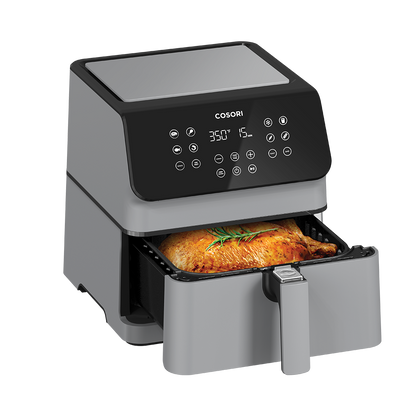 Cosori Pro II Air Fryer with basket pulled open revealing a whole roasted chicken in the 5.8-quart basket